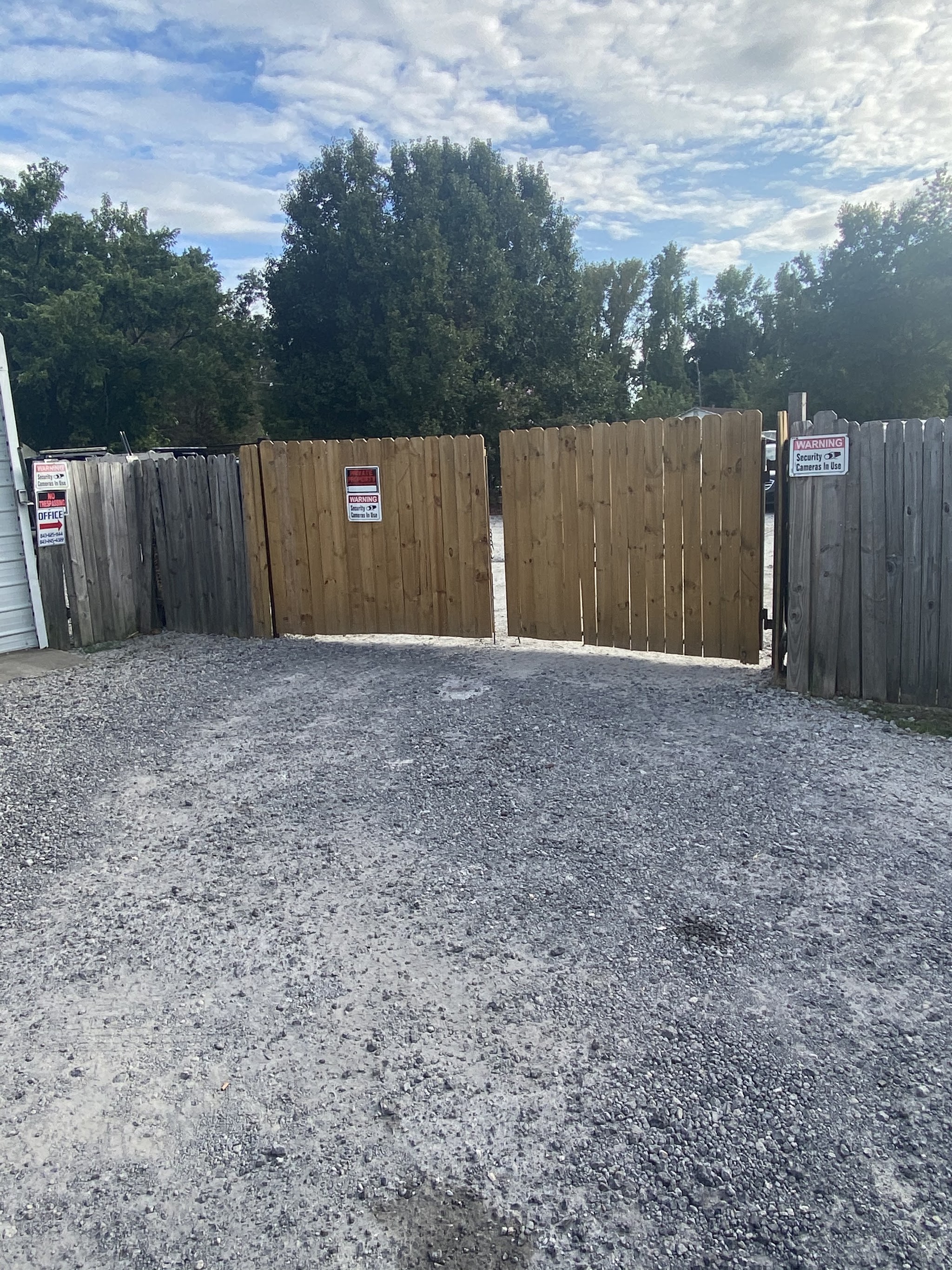 The wooden gate to our fenced yard with security camera signs